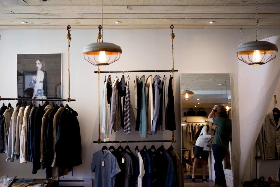 Interior de loja com araras de roupas e iluminação pendente