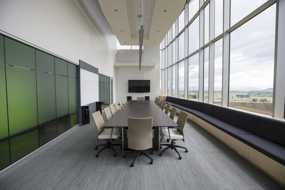 Sala de reunião clara com mesa comprida e janelas amplas